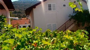 A building with a white facade, a red roof, and a staircase leading to a balcony. - Apartment Vido (Trpanj)
