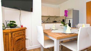 Una cucina moderna con mobili bianchi, un tavolo da pranzo in legno e un forno integrato.