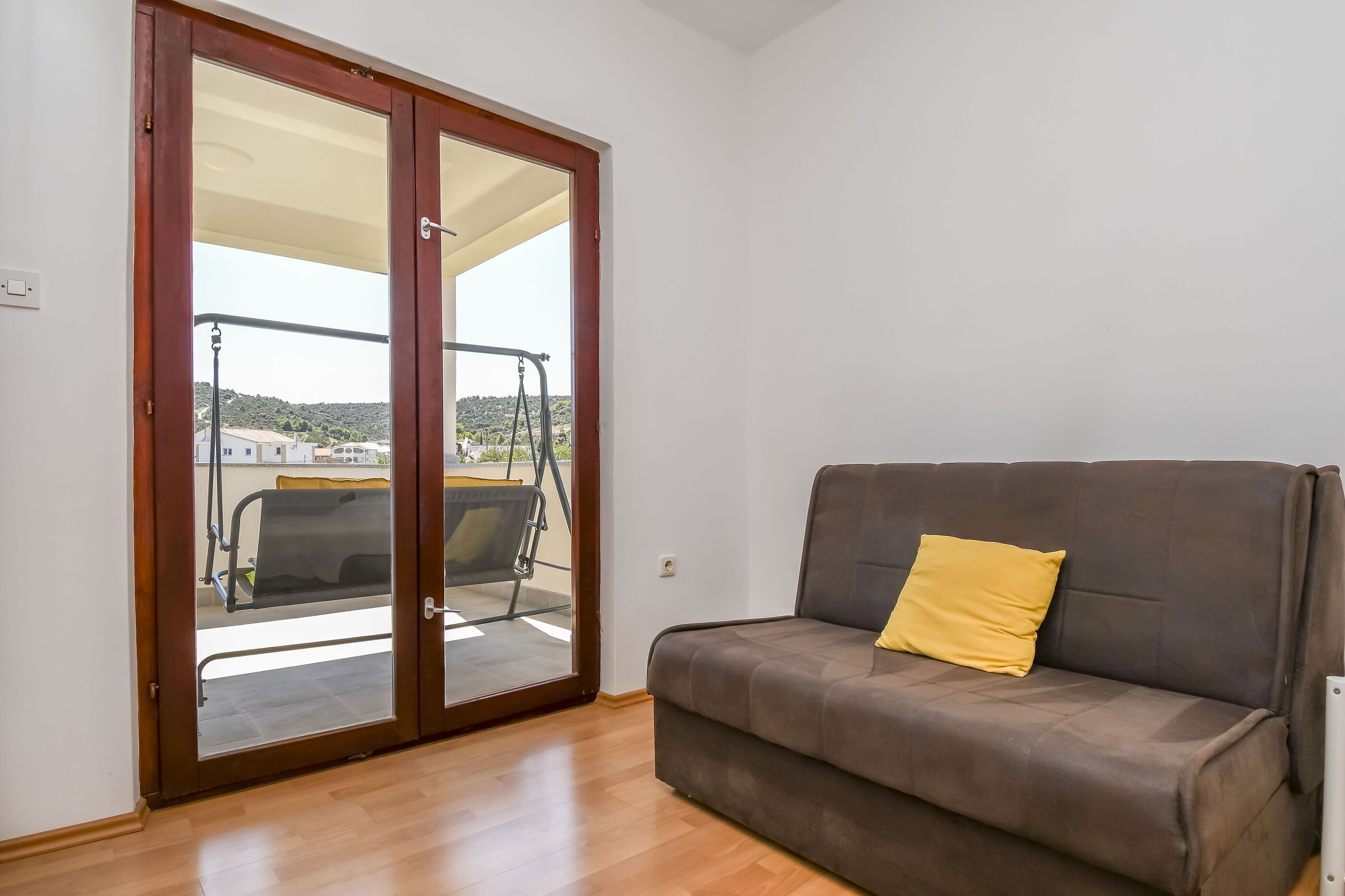 A room with a sliding glass door leading to a balcony with a swing chair.