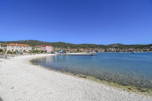 A coastal town with a pebble beach, clear waters, and buildings along the shore. - Apartments Deni (Marina)
