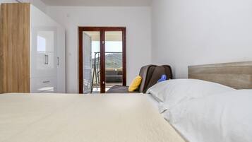 A hotel room with a bed, a wardrobe, a suitcase, and a balcony with a view.