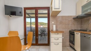 Eine kompakte Küche mit Essbereich, einem an der Wand montierten Fernseher und Blick ins Freie.