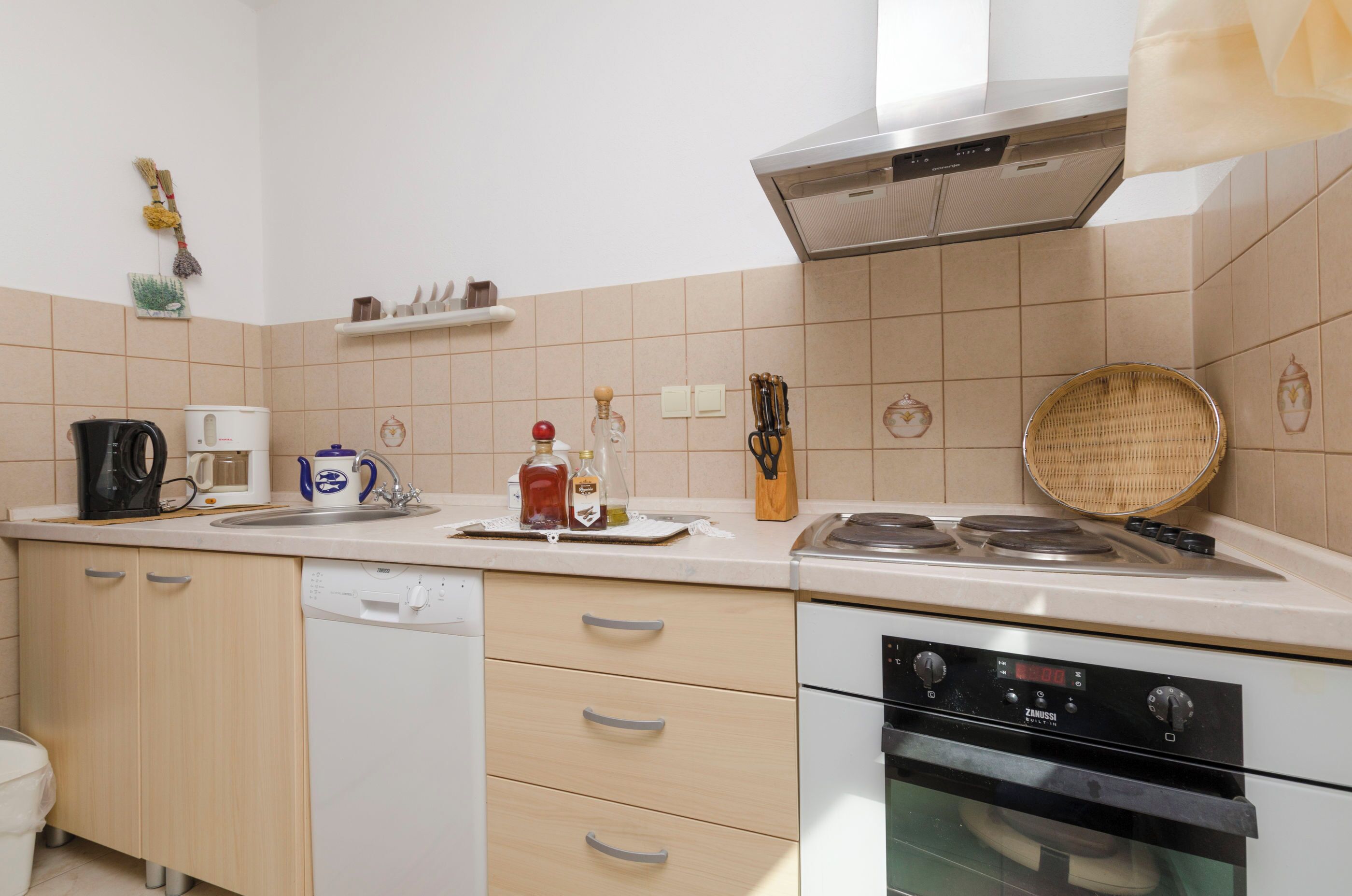 Une cuisine équipée d’un lave-vaisselle, d’une cuisinière et de divers ustensiles de cuisine.