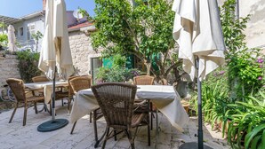 An outdoor patio with wicker furniture, white tablecloths, and umbrellas. - Apartments Draga (Jelsa)