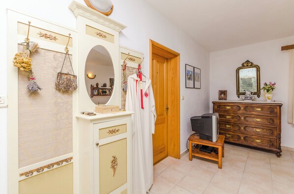 A room with a wooden door, a mirror, a dresser, and a television on a small table. - Apartments Draga (Jelsa)