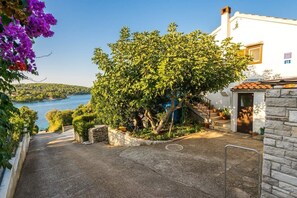 A coastal property with a stone staircase leading to a white building, a view of the sea, and a garden with various plants. - Apartment Mirja (Solta)