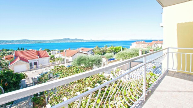 A balcony with a view of a coastal town, including houses and a clear blue sea. - Apartment Luce (Sveti Filip i Jakov)