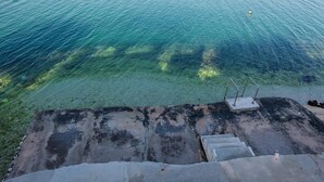 A concrete staircase leading to a clear water body, with a metal railing and a yellow buoy visible. - Apartments Anda (Trogir)