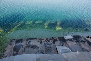 A concrete staircase leading to a clear water body, with a metal railing and a yellow buoy visible. - Apartments Anda (Trogir)