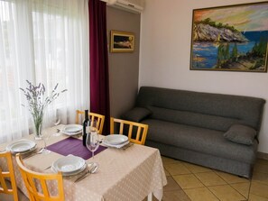 Un comedor con una mesa dispuesta para dos, un sofá y un cuadro en la pared.