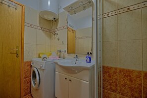 A bathroom with a washing machine, a sink, and a mirror. - Apartments Nela (Postira)