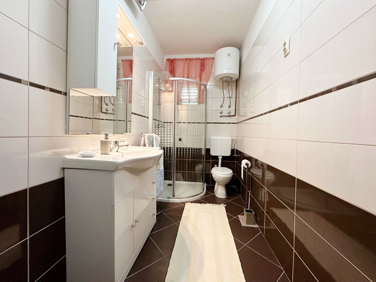 Un baño moderno con un lavamanos, espejo y retrete blancos.