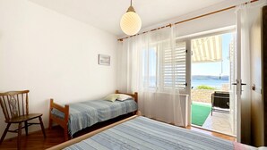 Une chambre à coucher avec un lit, une chaise, une fenêtre avec des rideaux et une vue sur l’extérieur.