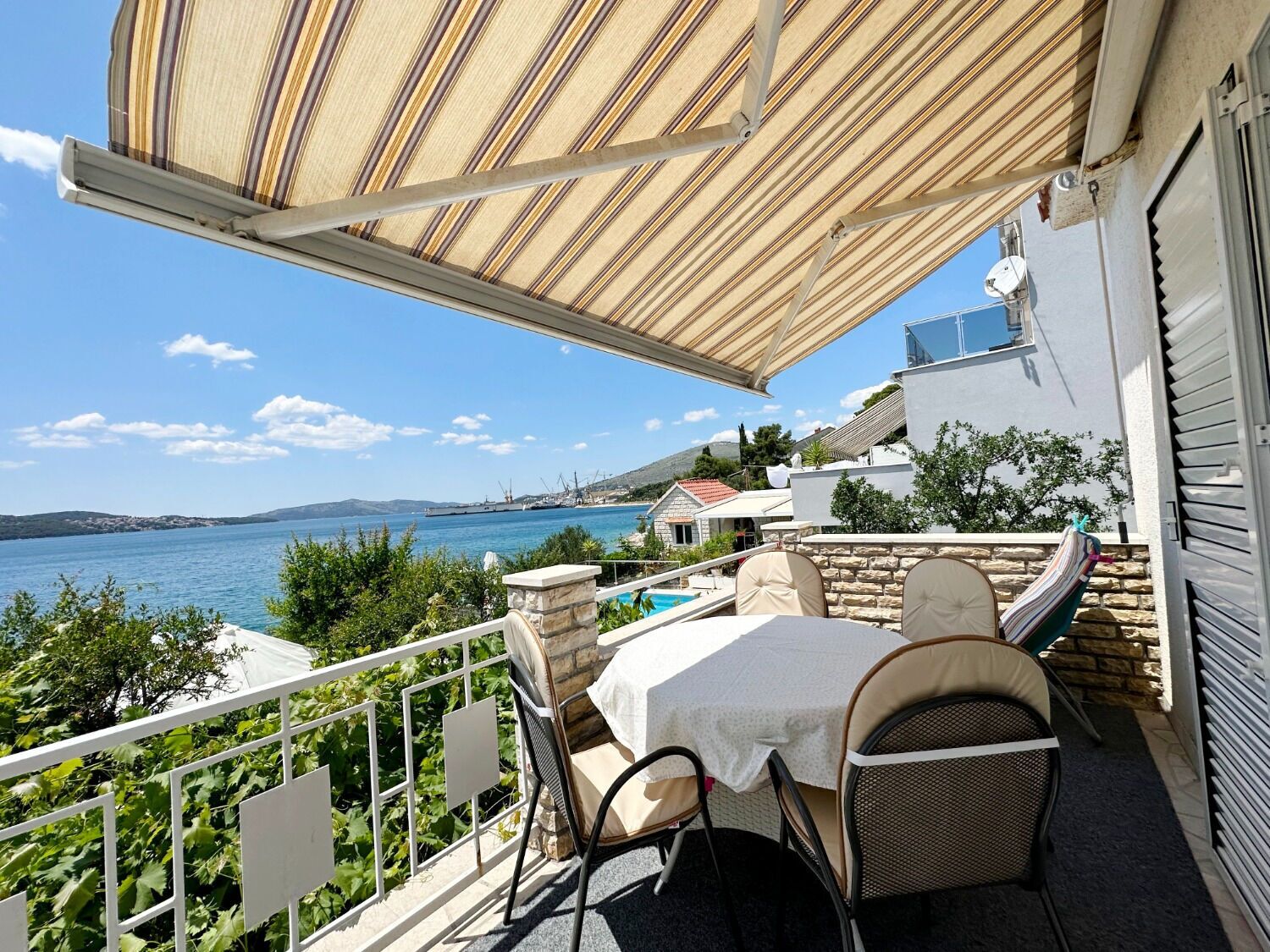 Een balkon met een tafel en stoelen, met uitzicht op een wateroppervlak en een schip in de verte.