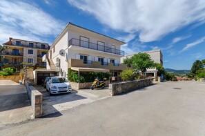 A multi-story residential building with a garage, a parked car, and a motorcycle. - Apartment Tonka (Jelsa)