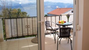 Ein Balkon mit Tisch und Stühlen, Blick auf einen See und Berge im Hintergrund.