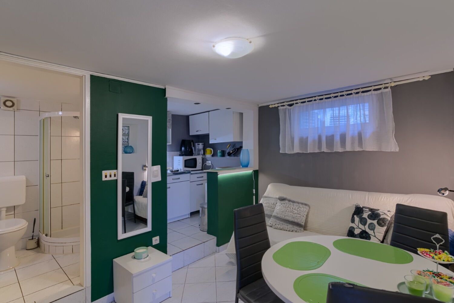 A compact living space with a kitchenette, a dining area, and a bathroom.