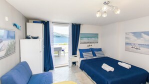 Una camera da letto con un letto, un divano, una scrivania e vista sul mare.