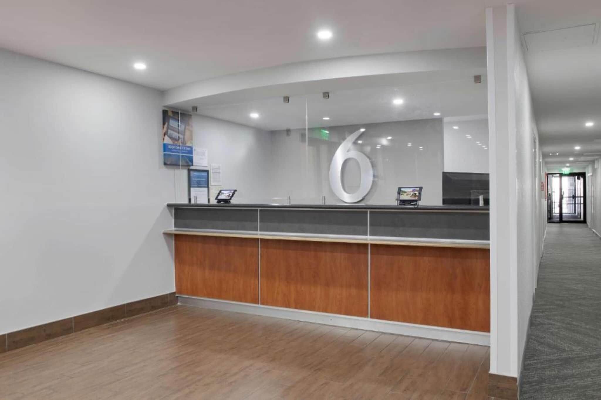 A reception desk with a wooden panel design, a large circular logo, and a digital screen.