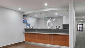 A modern reception area with a wooden counter, a large white number '6' sign, and a corridor leading to another part of the building. - 2 Full Beds|Mobil Access|Nsmk|Micfridg (Atlanta)
