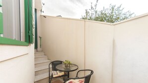 A small outdoor patio with a round table and two chairs, a potted plant, and a staircase leading to an upper level. - Apartments Brane (Postira)