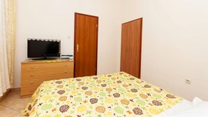 A bedroom with a bed, a dresser, a television, and two wardrobes. - Apartments Brane (Postira)