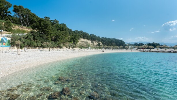 A beach with clear water, a sandy shore, and a forested hillside. - Apartment Maria (Split)