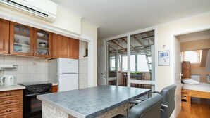 A kitchen with a built-in island, a refrigerator, a stove, and wooden cabinets. - Apartment Maria (Split)