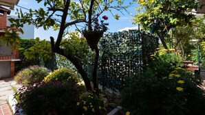 A garden with a tree, a hanging plant, and various flowers. - Apartment Maria (Split)