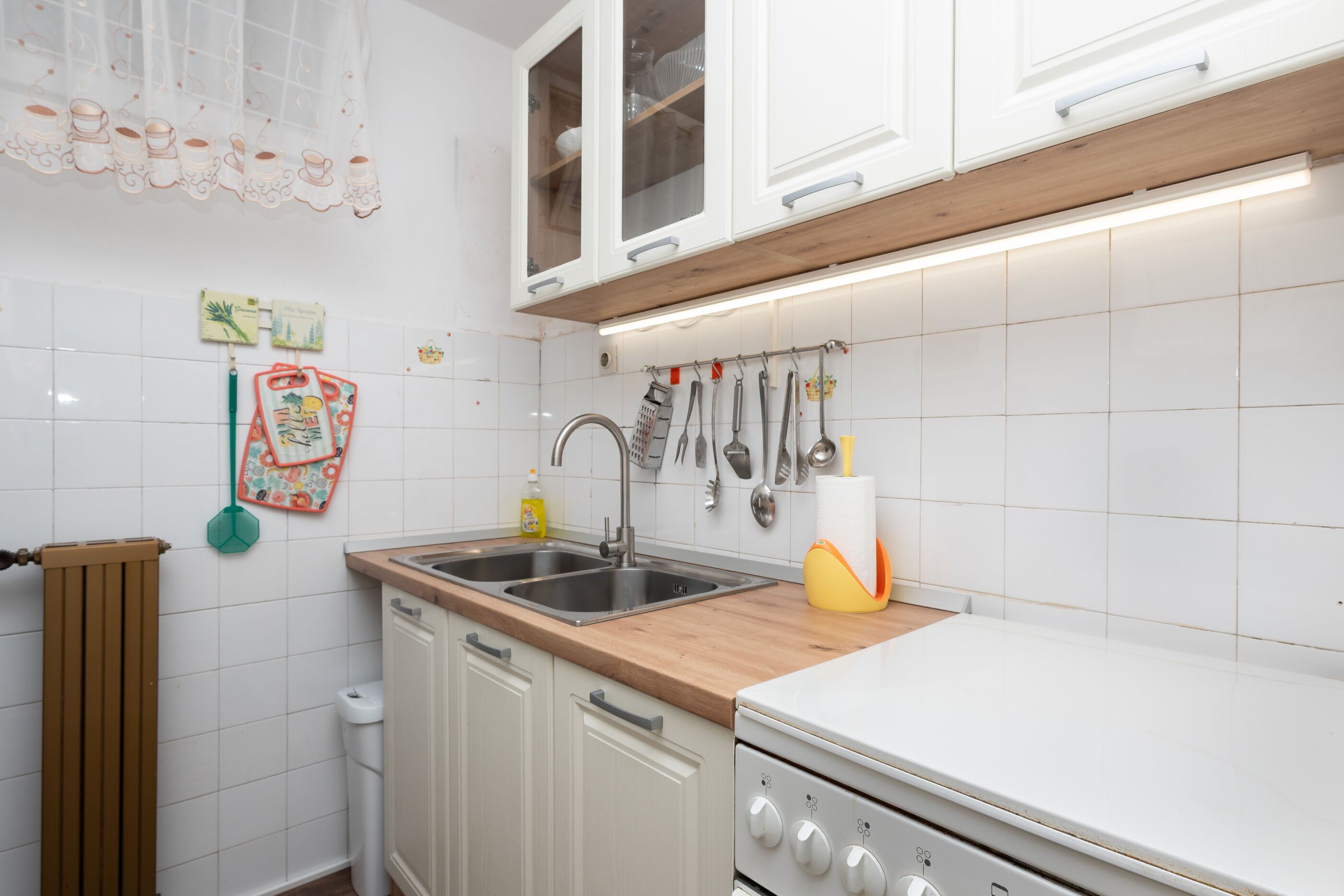 A kitchen with white cabinets, a wooden countertop, a sink, and a stove.