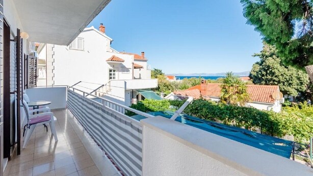 Un balcon donnant sur les maisons voisines et un ciel dégagé.