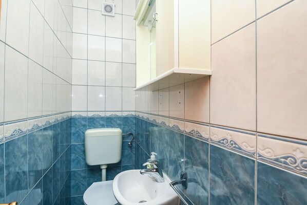 A bathroom with a white sink, a toilet, and a mirror above the sink. - Apartments Vesna (Seget)