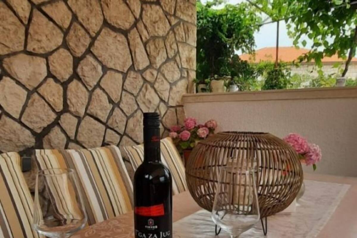 Una mesa con una botella de vino, dos cuencos de frutos secos y una cesta de mimbre con flores.
