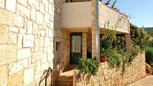 A stone building with a balcony, a staircase leading to the entrance, and a sign reading "FONTALE." - Apartments Kat (Supetar)