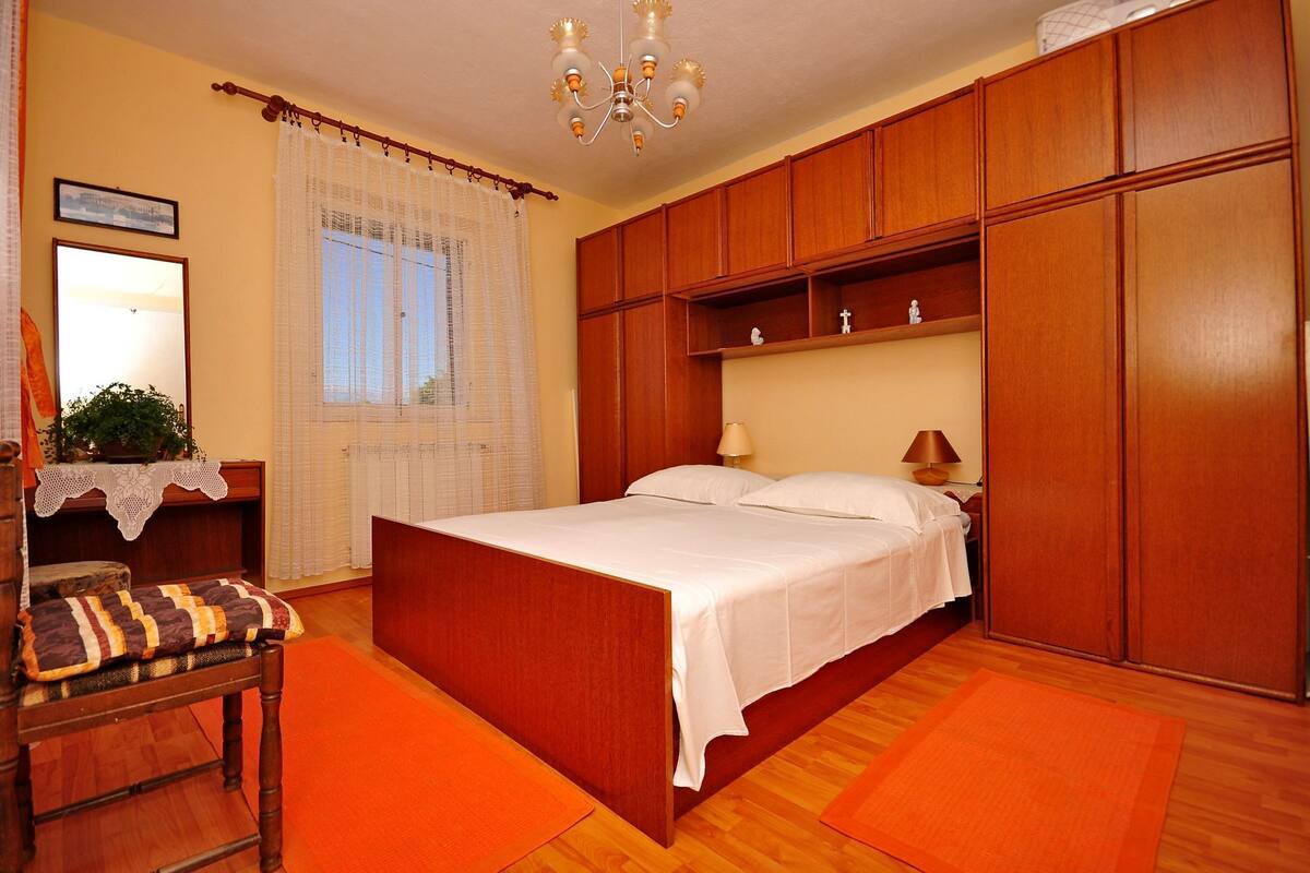 A bedroom with a wooden bed, a nightstand, a chair, and a wardrobe.