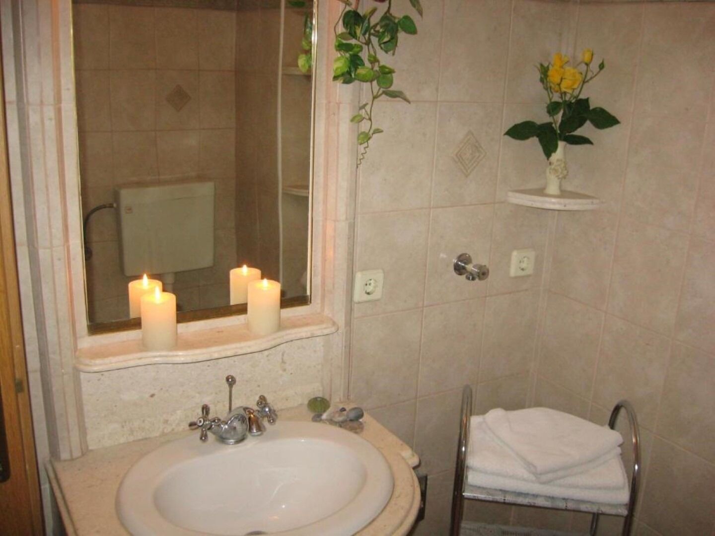 A bathroom with a sink, mirror, and two lit candles.