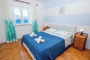A bedroom with a bed, two bedside tables, a window with curtains, and a wall-mounted picture. - Apartments Sova (Postira)
