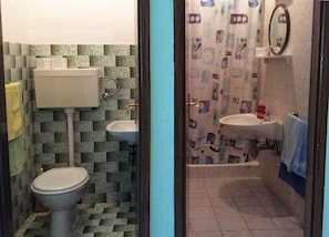 A bathroom with a toilet, sink, and shower area. - Apartments Sova (Postira)