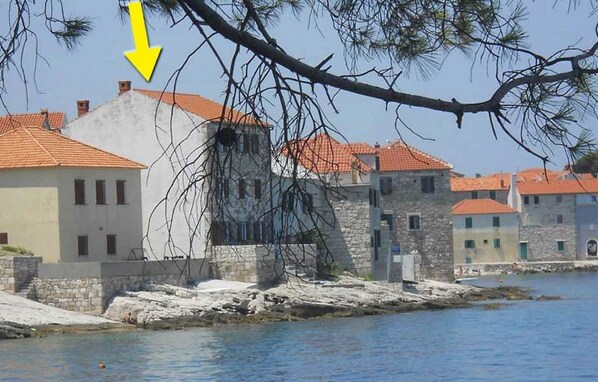 A coastal village with stone buildings, a clear sky, and a body of water. - Apartments Sova (Postira)