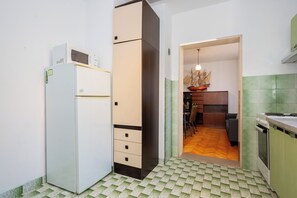 Eine kleine Küche mit Kühlschrank, Schränken und einem Essbereich mit Stuhl und Tisch.