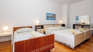 Habitación de hotel con dos camas, un cuadro, un espejo y un escritorio con una lámpara.