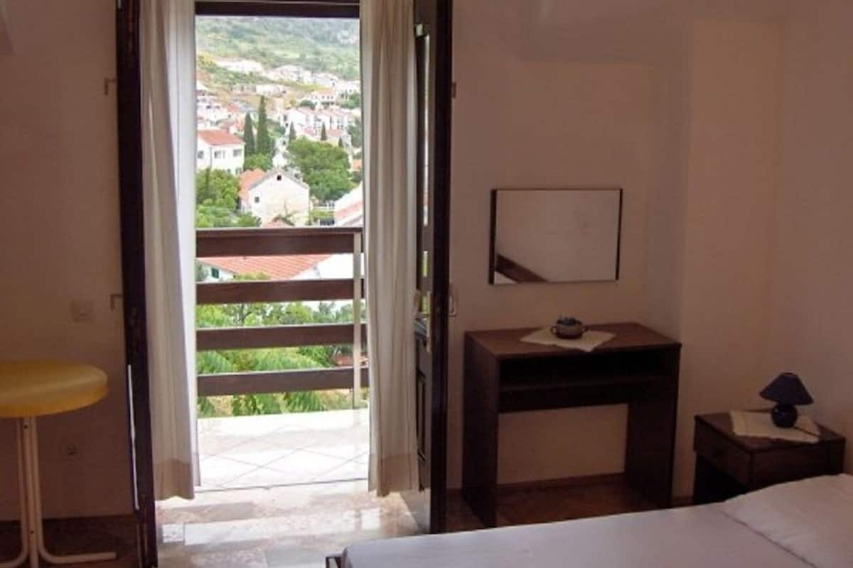A hotel room with a balcony, a bed, a desk, and a chair.