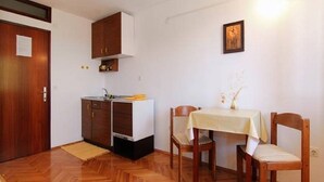 Una cucina compatta con mobili in legno, un piccolo bancone e un'area pranzo con tavolo e sedie.