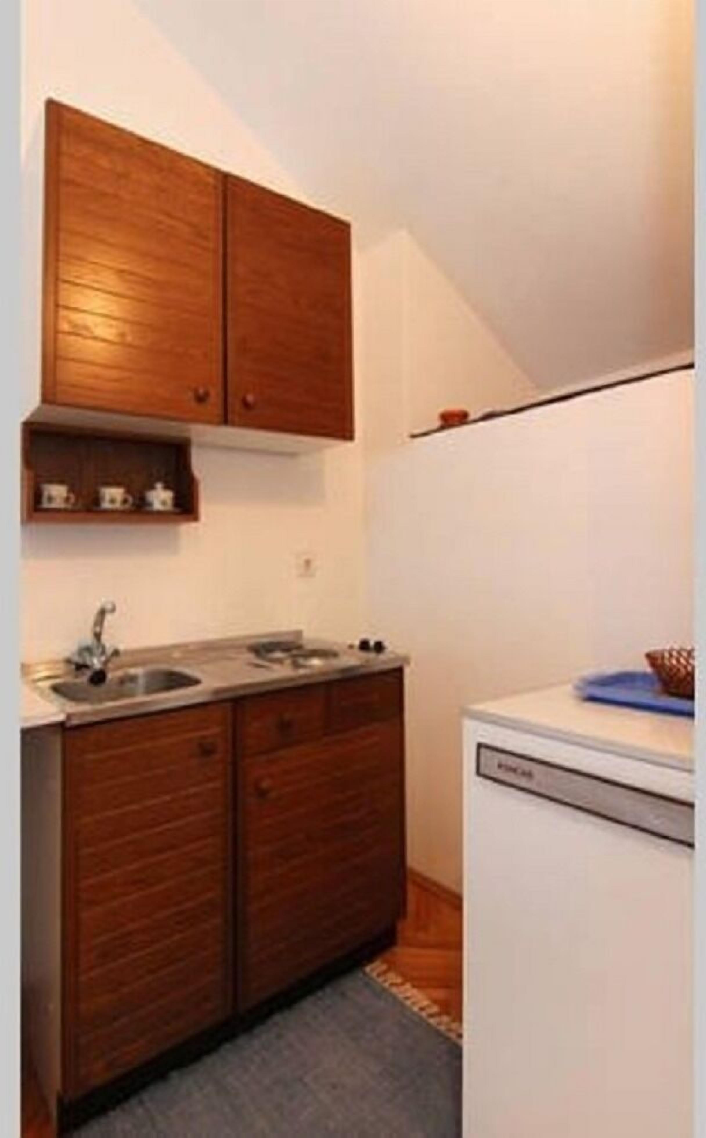 A compact kitchen with wooden cabinets, a sink, and a dishwasher.
