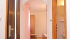 A narrow hallway with wooden doors and a tiled floor, leading to a bathroom with a sink and a toilet. - House Paulo1 (Vis)