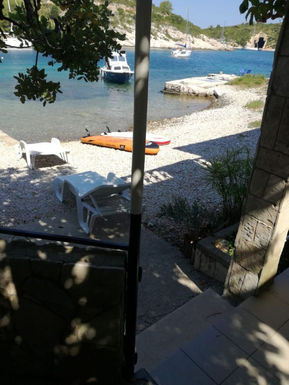 A view of a beach with boats, a lifeguard stand, and beach chairs.