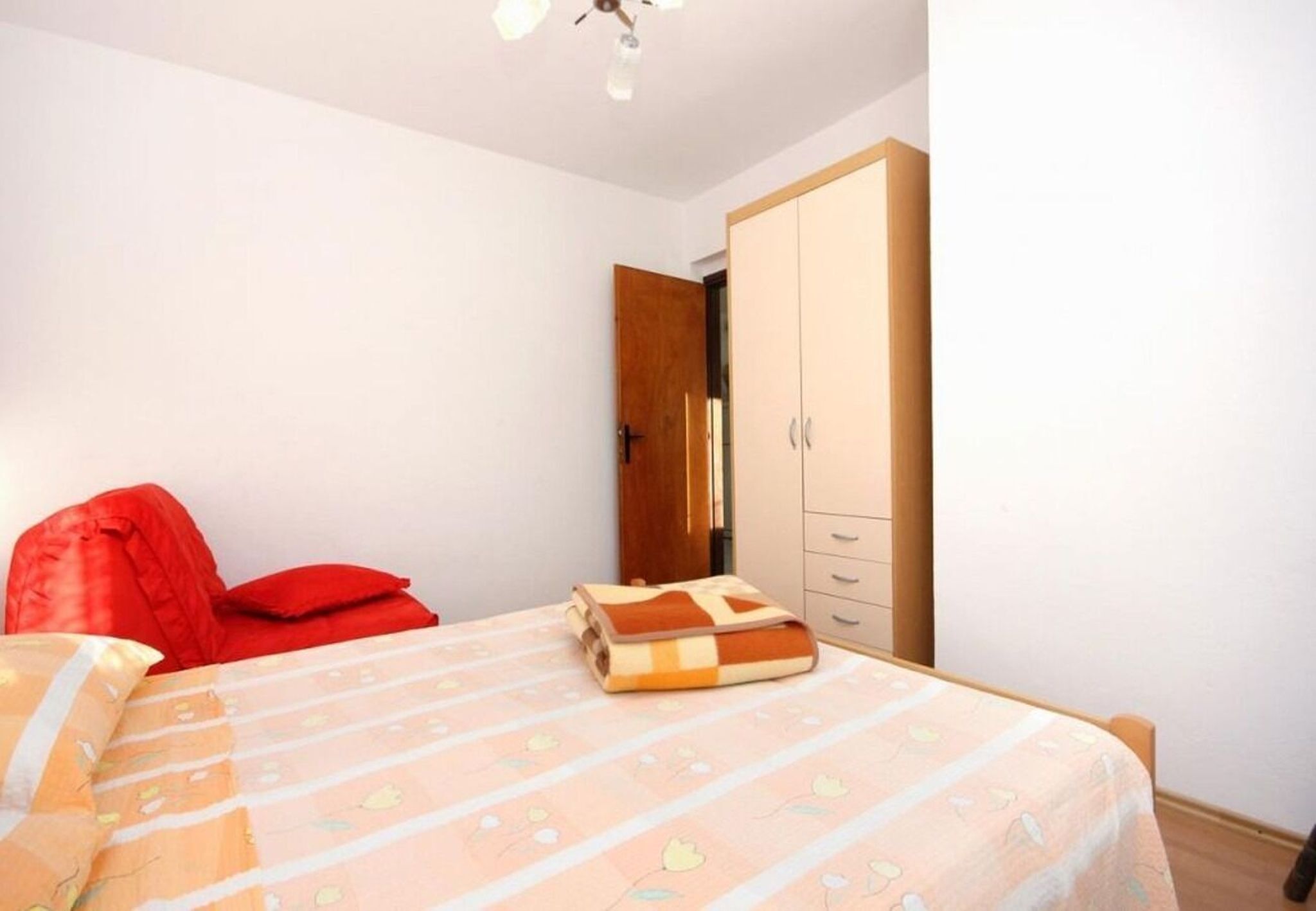 A bedroom with a bed, a wardrobe, and a door.