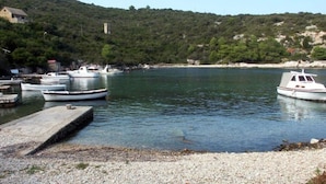 Ein Yachthafen mit mehreren vertäuten Booten, umgeben von hügeliger Landschaft und blauem Himmel.
