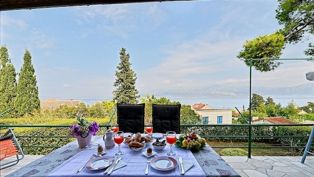 Un tavolo apparecchiato per due con vista sul mare e sulle colline.