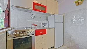 Una cucina compatta con piano cottura a gas, forno, microonde e frigorifero.